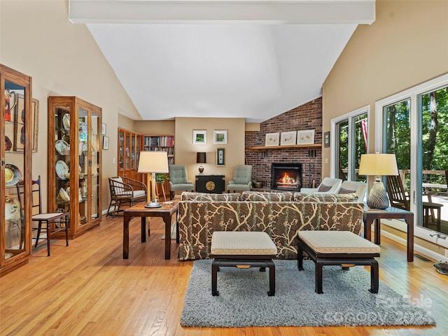 living room with a fireplace, beamed ceiling, brick wall, and light hardwood / wood-style floors