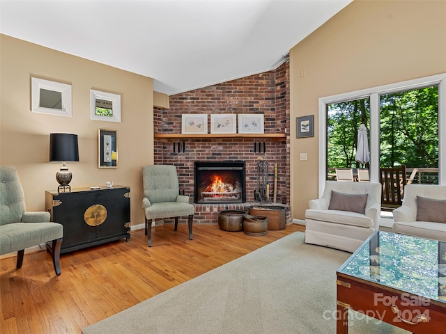 living room featuring lofted ceiling, light hardwood / wood-style flooring, and a brick fireplace