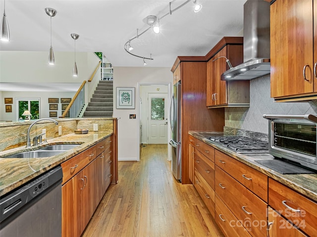 kitchen featuring appliances with stainless steel finishes, light hardwood / wood-style flooring, wall chimney range hood, light stone counters, and rail lighting