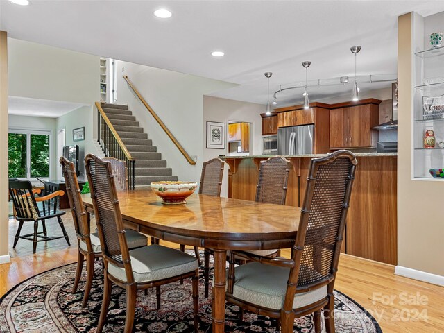 dining area with light hardwood / wood-style flooring and track lighting