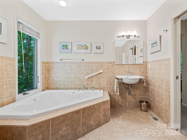 bathroom with tile patterned flooring, tile walls, sink, and a relaxing tiled tub