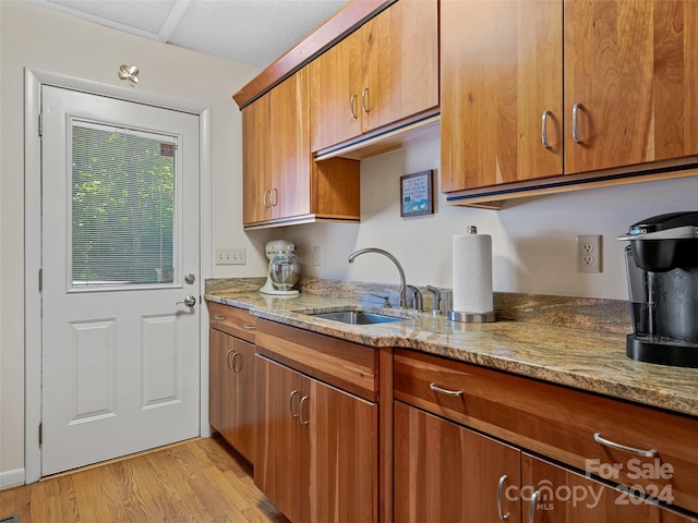 kitchen with light stone countertops, sink, and light wood-type flooring