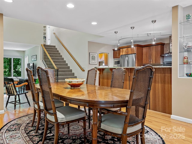 dining area with track lighting and light hardwood / wood-style floors