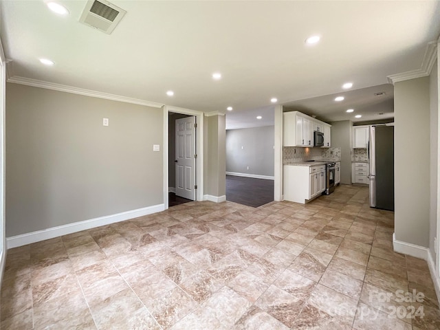 kitchen with white cabinets, appliances with stainless steel finishes, tasteful backsplash, and ornamental molding