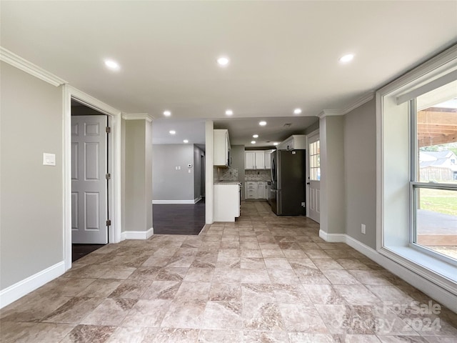 kitchen with stainless steel fridge, white cabinetry, a wealth of natural light, and tasteful backsplash