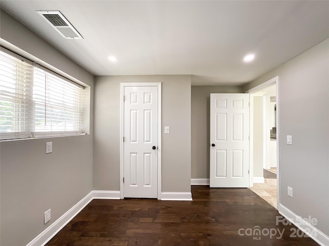 unfurnished bedroom with dark hardwood / wood-style flooring and a closet