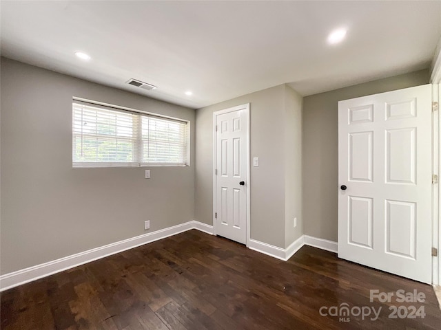 unfurnished bedroom with dark hardwood / wood-style floors and a closet