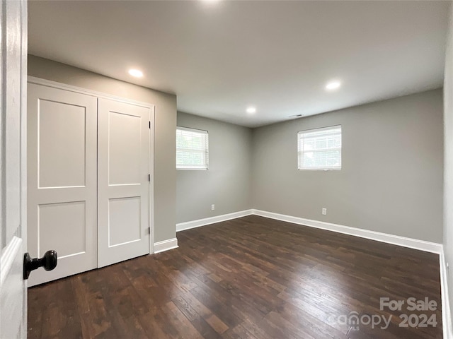 basement with a healthy amount of sunlight and dark hardwood / wood-style floors