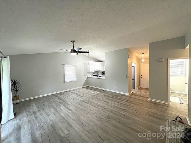 unfurnished living room with ceiling fan, wood-type flooring, lofted ceiling, and a textured ceiling