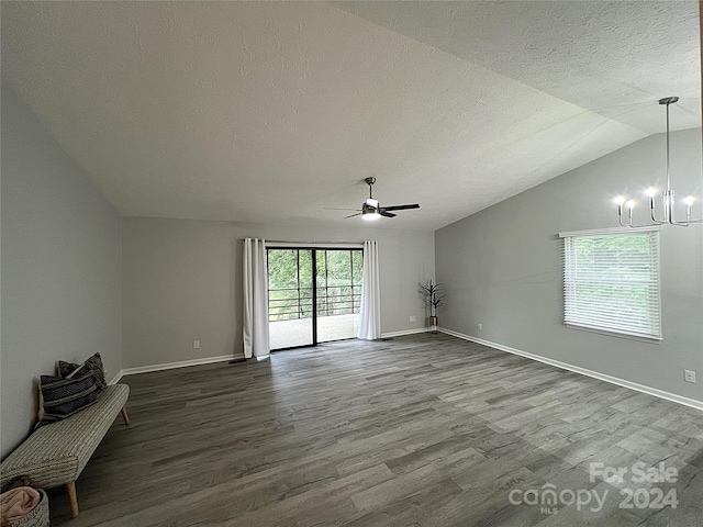 unfurnished room featuring ceiling fan with notable chandelier, wood-type flooring, lofted ceiling, and a textured ceiling