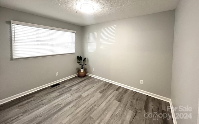 spare room with wood-type flooring and a textured ceiling