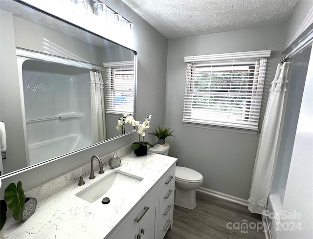 full bathroom featuring toilet, vanity, hardwood / wood-style flooring, a textured ceiling, and shower / bath combo with shower curtain