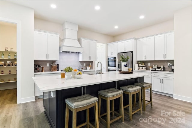 kitchen with appliances with stainless steel finishes, white cabinets, and an island with sink