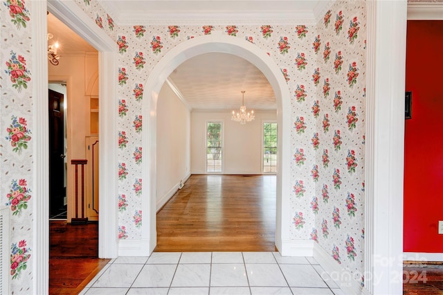 corridor featuring ornamental molding, light tile patterned floors, and a chandelier