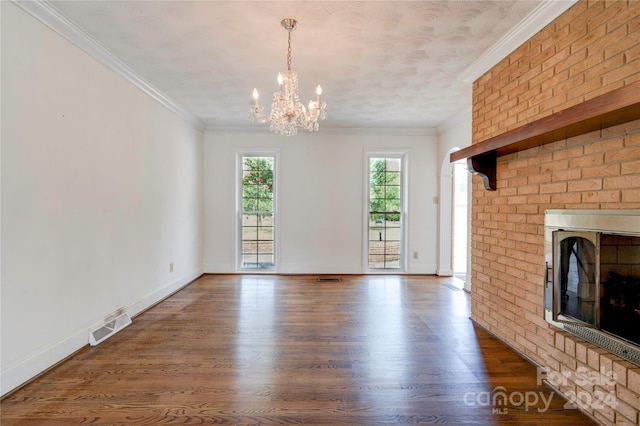 unfurnished living room featuring crown molding, a fireplace, dark hardwood / wood-style floors, and a notable chandelier