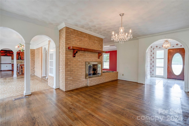 unfurnished living room featuring hardwood / wood-style floors, a brick fireplace, plenty of natural light, and ornamental molding