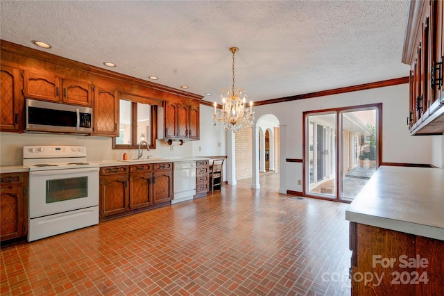 kitchen featuring ornamental molding, a textured ceiling, white appliances, sink, and decorative light fixtures