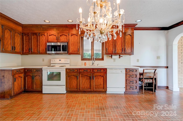 kitchen featuring sink, hanging light fixtures, an inviting chandelier, a textured ceiling, and white appliances