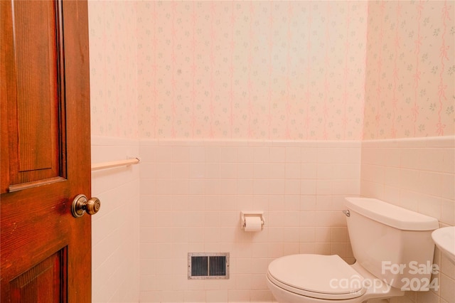 bathroom with toilet and tile walls