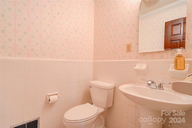 bathroom with sink, ornamental molding, tile walls, and toilet