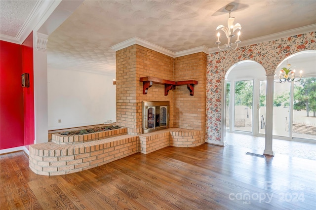 unfurnished living room featuring hardwood / wood-style flooring, crown molding, and an inviting chandelier