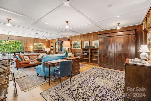 living room featuring wooden walls, coffered ceiling, and light wood-type flooring