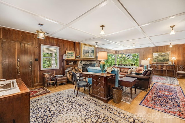 living room featuring light hardwood / wood-style floors, coffered ceiling, plenty of natural light, and wooden walls