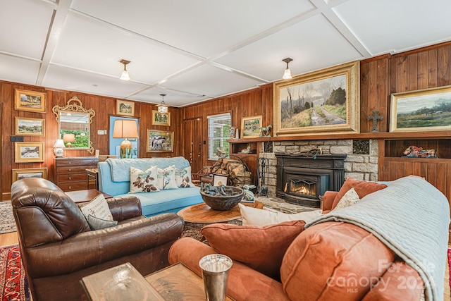 living room with coffered ceiling, a stone fireplace, and wood walls