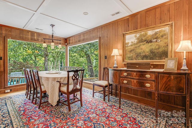 dining space with wood walls and coffered ceiling