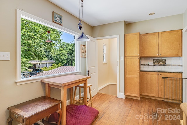 kitchen featuring backsplash, light hardwood / wood-style flooring, and hanging light fixtures