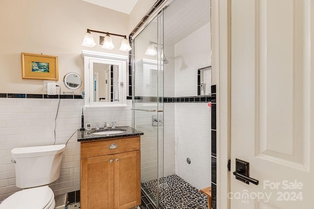 bathroom featuring toilet, an enclosed shower, vanity, and tile walls