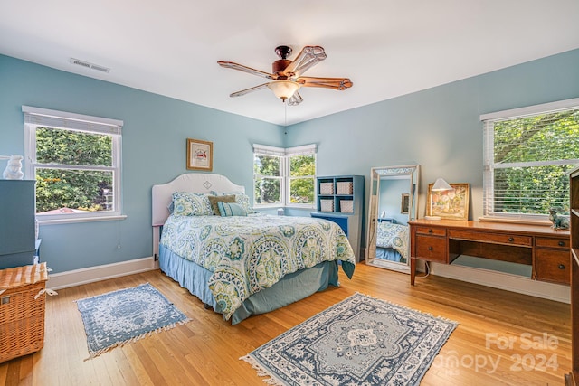 bedroom featuring multiple windows, hardwood / wood-style flooring, and ceiling fan