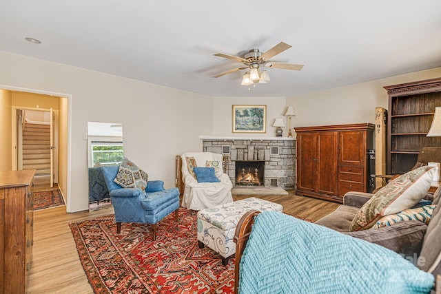 living room with ceiling fan, light hardwood / wood-style flooring, and a fireplace