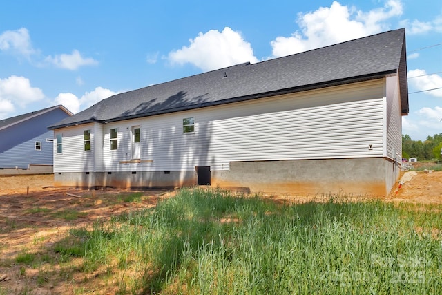 back of house with roof with shingles and crawl space