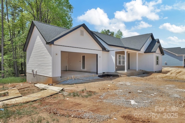 modern farmhouse style home featuring covered porch, roof with shingles, and a garage