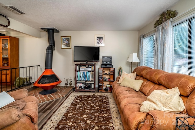 living room with a wood stove, a textured ceiling, and hardwood / wood-style floors