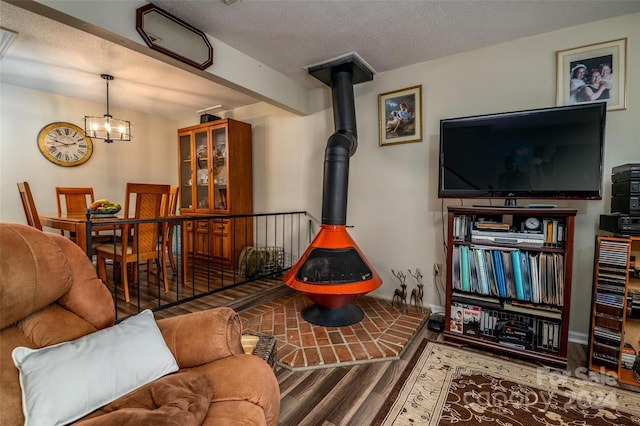 living room featuring a textured ceiling, a notable chandelier, hardwood / wood-style floors, and a wood stove