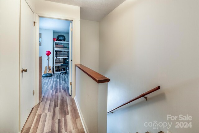 corridor with hardwood / wood-style flooring and a textured ceiling