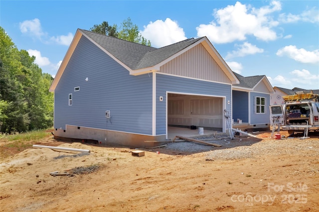 view of side of home with a garage and roof with shingles