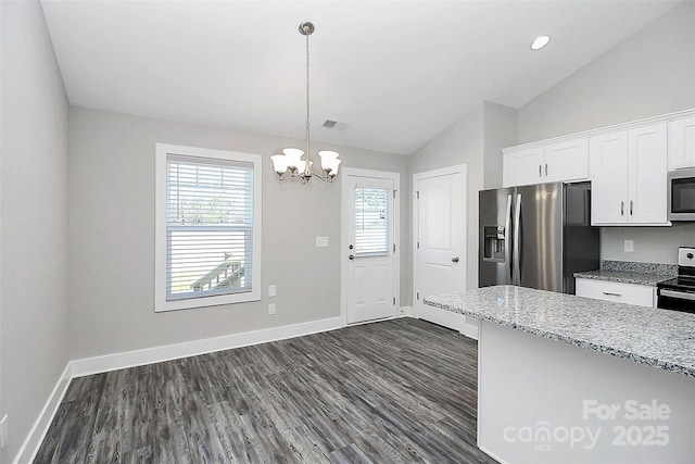 kitchen with lofted ceiling, stainless steel appliances, white cabinetry, dark wood-type flooring, and a notable chandelier