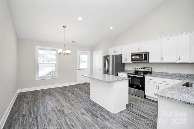 kitchen with stainless steel appliances, a center island, an inviting chandelier, and white cabinetry