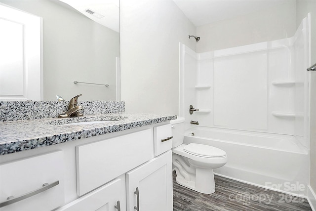 bathroom with toilet, visible vents, wood finished floors, vanity, and shower / tub combination