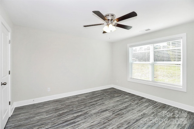 spare room with baseboards, dark wood-style floors, and ceiling fan