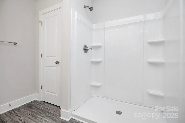 full bath featuring baseboards, walk in shower, and wood finished floors