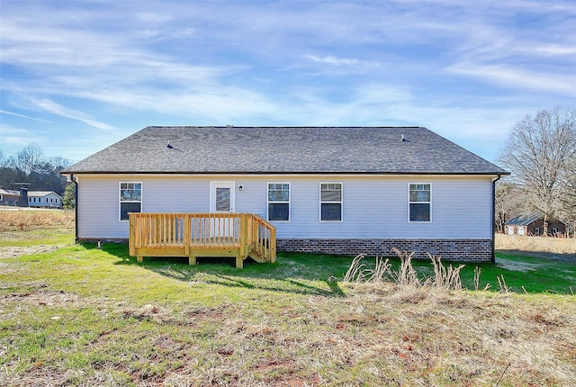 rear view of house featuring a lawn, roof with shingles, and a deck