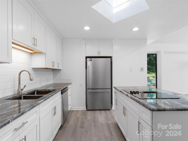 kitchen with sink, white cabinetry, appliances with stainless steel finishes, and dark stone countertops