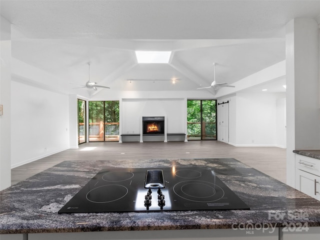 kitchen with ceiling fan, white cabinets, black electric stovetop, and a healthy amount of sunlight