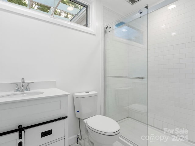 bathroom featuring toilet, vanity, and a shower with door