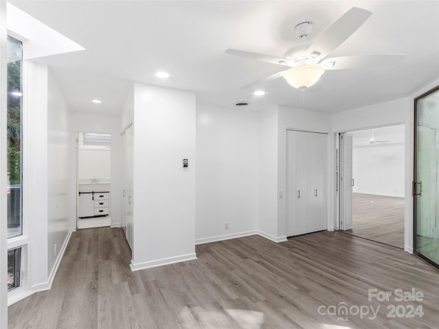 unfurnished bedroom with ceiling fan, two closets, and light wood-type flooring