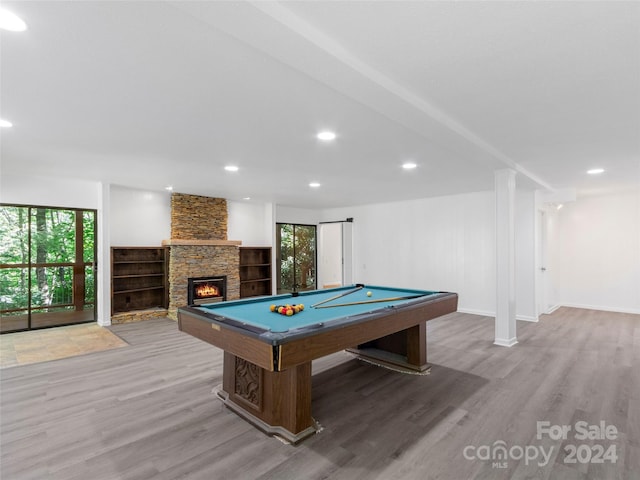 playroom with pool table, a stone fireplace, and light hardwood / wood-style floors